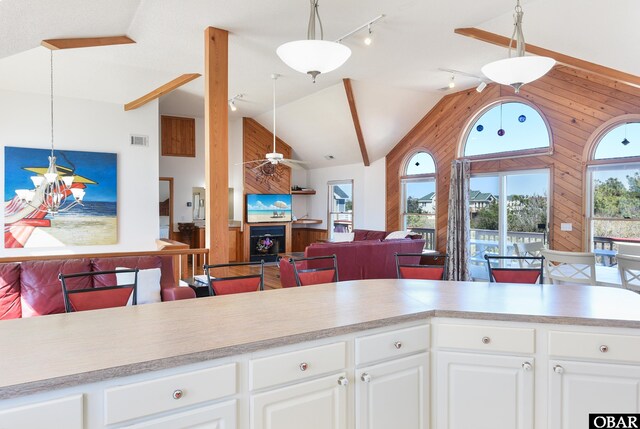 living room with lofted ceiling, light wood-type flooring, wood walls, and wainscoting