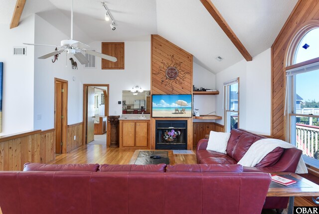 living room featuring vaulted ceiling, light wood finished floors, and wooden walls