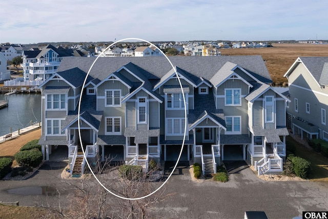 view of front of house featuring a water view, a shingled roof, and a residential view