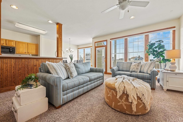 living area featuring recessed lighting, light colored carpet, and ceiling fan with notable chandelier