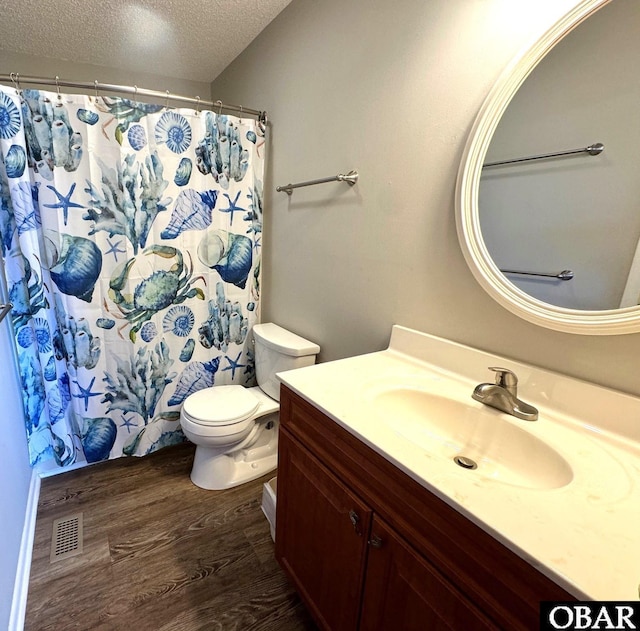 full bath with toilet, vanity, wood finished floors, a textured ceiling, and visible vents