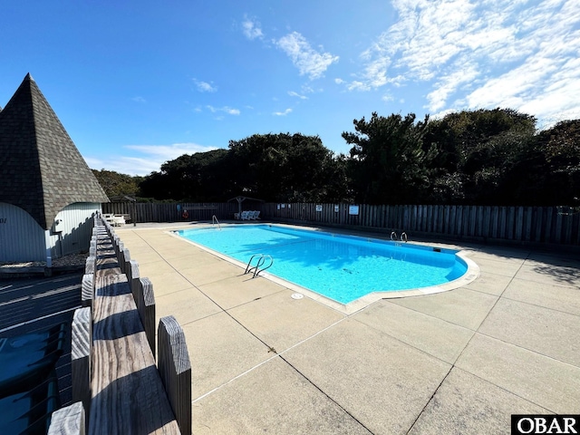 community pool with a fenced backyard and a patio area