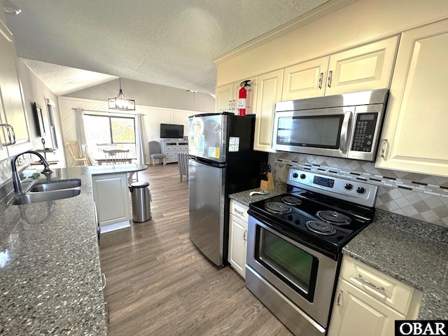 kitchen featuring a sink, backsplash, wood finished floors, appliances with stainless steel finishes, and a textured ceiling