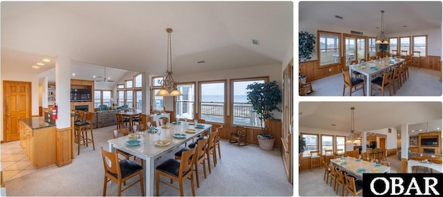 dining room with light carpet, wooden walls, a water view, a fireplace, and a notable chandelier