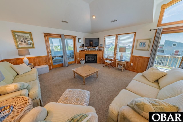 living area with visible vents, wainscoting, and wood walls