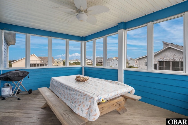 sunroom / solarium featuring a residential view, hardwood / wood-style floors, and ceiling fan