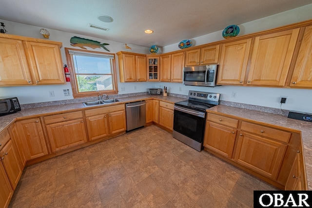 kitchen with visible vents, recessed lighting, a sink, glass insert cabinets, and appliances with stainless steel finishes