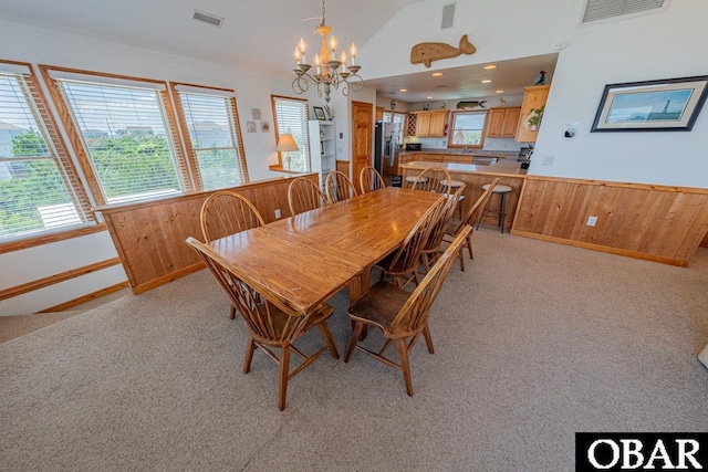 dining room featuring a wainscoted wall, wooden walls, visible vents, and light carpet