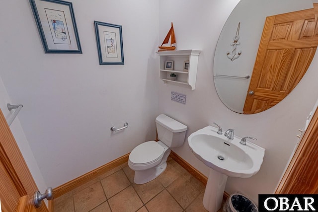 bathroom featuring a sink, baseboards, toilet, and tile patterned flooring