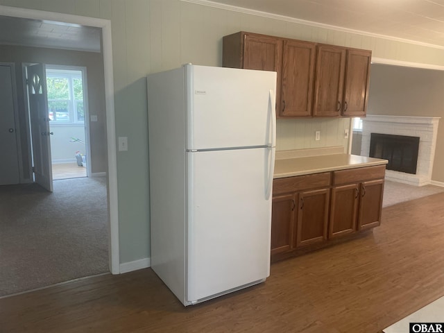 kitchen with brown cabinets, wood finished floors, freestanding refrigerator, carpet, and light countertops