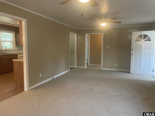 interior space featuring ornamental molding, a sink, a ceiling fan, and light colored carpet