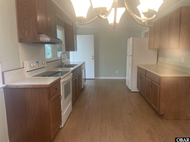 kitchen featuring white appliances, light countertops, a sink, and wood finished floors