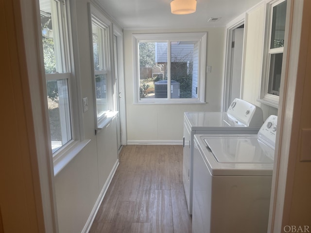 washroom with laundry area, light wood finished floors, baseboards, visible vents, and washer and dryer