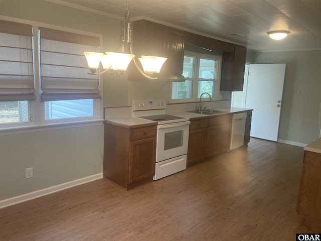 kitchen with white appliances, brown cabinetry, decorative light fixtures, light countertops, and a sink