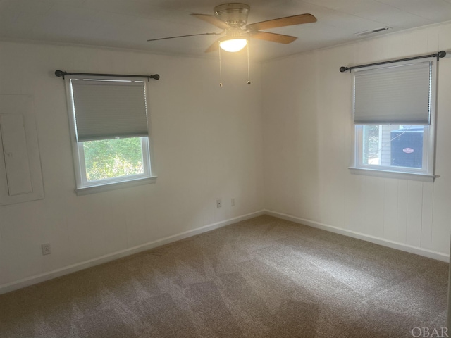 spare room featuring carpet, visible vents, ceiling fan, electric panel, and baseboards