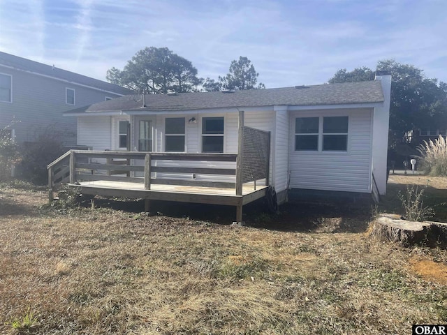 view of front of home featuring roof with shingles, a deck, and a front lawn