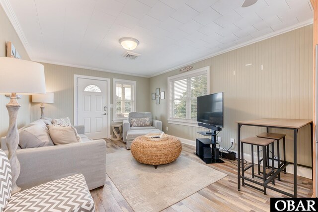 living room featuring visible vents, baseboards, wood finished floors, and crown molding