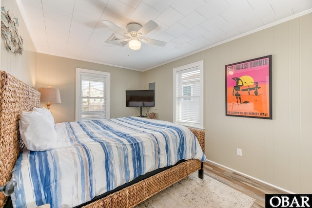 bedroom with baseboards, wood finished floors, a ceiling fan, and crown molding