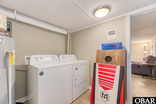 laundry room featuring light wood finished floors, electric water heater, crown molding, laundry area, and washer and dryer