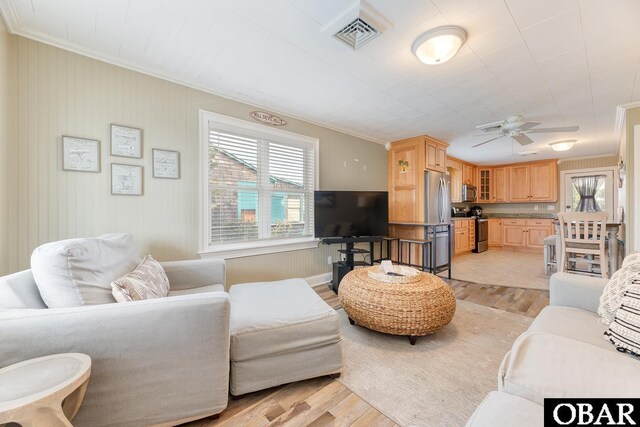 living area with light wood finished floors, visible vents, a wealth of natural light, and ornamental molding