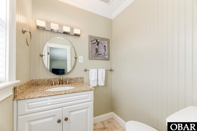 half bathroom with vanity, visible vents, baseboards, ornamental molding, and toilet