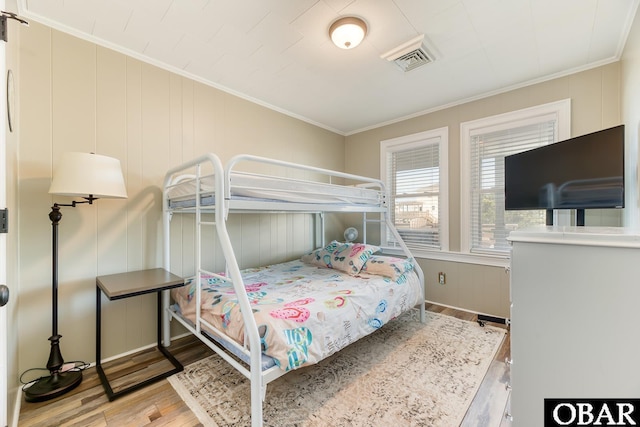 bedroom with visible vents, wood finished floors, and ornamental molding