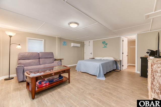 bedroom featuring light wood-style flooring, an AC wall unit, and baseboards