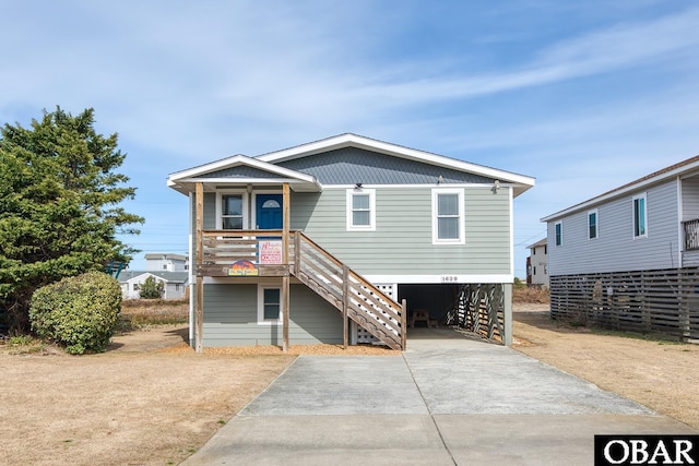 view of front of house with stairs, a carport, covered porch, and driveway