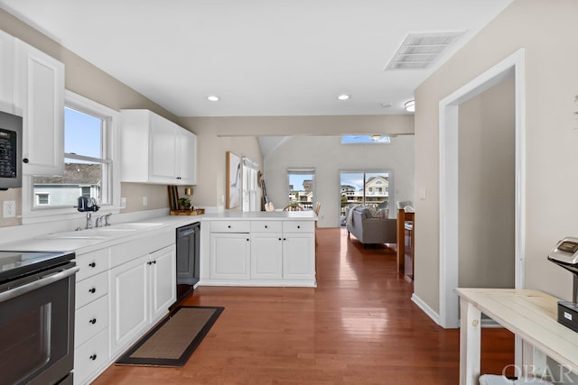 kitchen featuring a peninsula, electric range, visible vents, black dishwasher, and light countertops