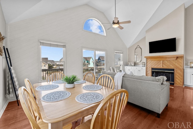 dining area with high vaulted ceiling, dark wood-style flooring, a fireplace, and a ceiling fan