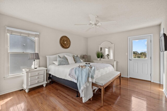 bedroom featuring a ceiling fan, a textured ceiling, baseboards, and wood finished floors