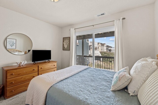 bedroom with carpet floors, access to outside, visible vents, and a textured ceiling