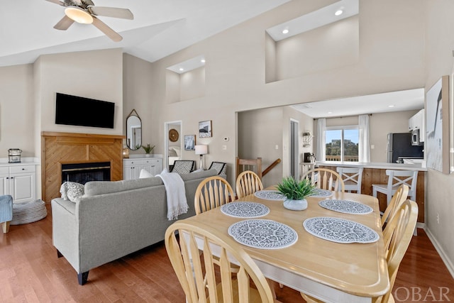 dining room with high vaulted ceiling, wood finished floors, and a high end fireplace