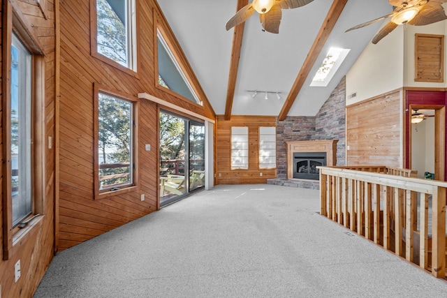 living room with high vaulted ceiling, wood walls, a fireplace, beam ceiling, and carpet