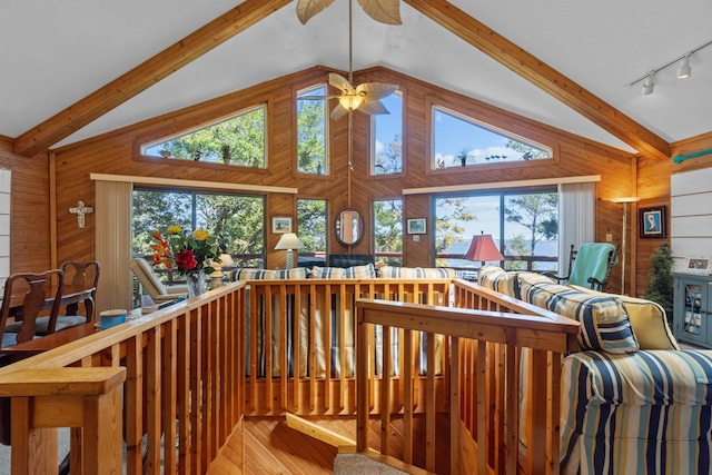 staircase with wooden walls, ceiling fan, beamed ceiling, wood finished floors, and high vaulted ceiling