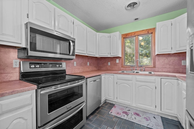 kitchen with a sink, stainless steel appliances, light countertops, and white cabinets