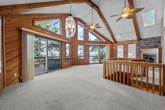 living area with beamed ceiling, carpet, wood walls, a fireplace, and high vaulted ceiling