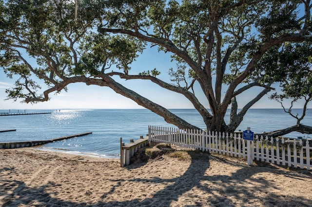 property view of water featuring fence and a beach view