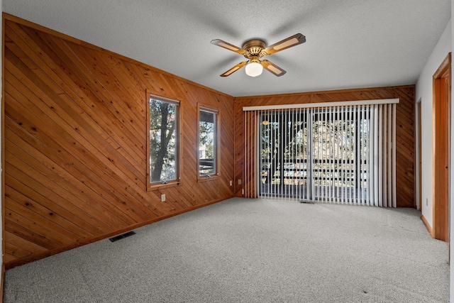 carpeted empty room featuring ceiling fan, a textured ceiling, visible vents, and baseboards