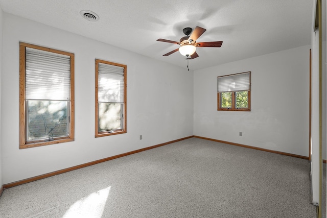 carpeted empty room featuring a ceiling fan, visible vents, a textured ceiling, and baseboards