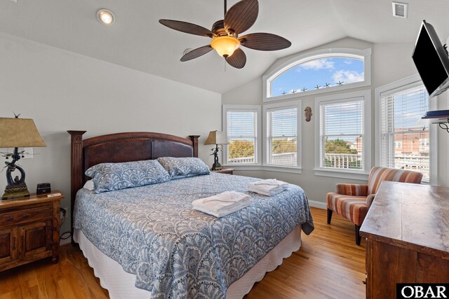 bedroom featuring a ceiling fan, visible vents, vaulted ceiling, and light wood-style floors