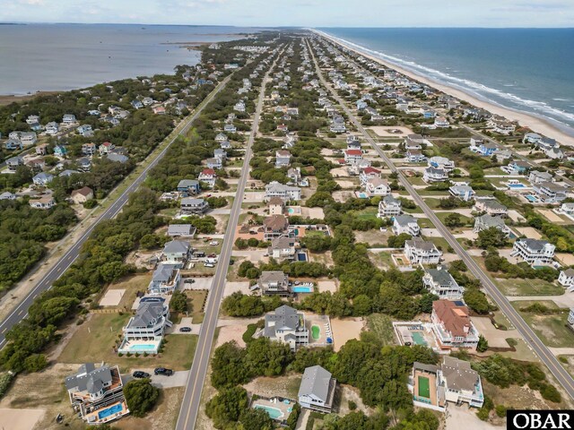 drone / aerial view featuring a water view, a residential view, and a beach view