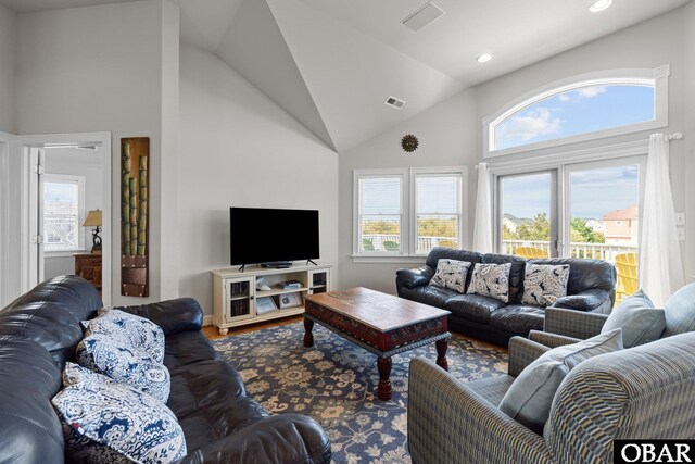 living area with high vaulted ceiling, visible vents, and a healthy amount of sunlight
