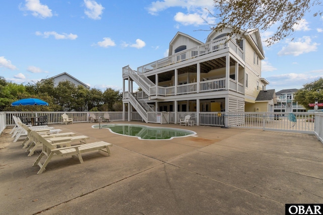 back of property with a fenced in pool, a patio area, fence, and stairway