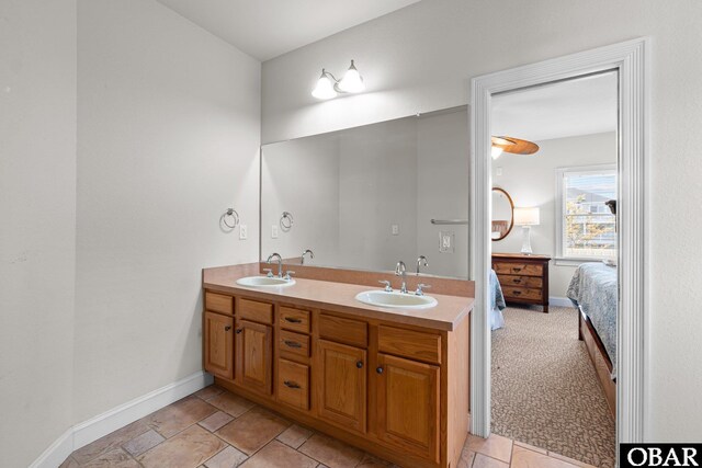 ensuite bathroom featuring baseboards, a sink, connected bathroom, and double vanity