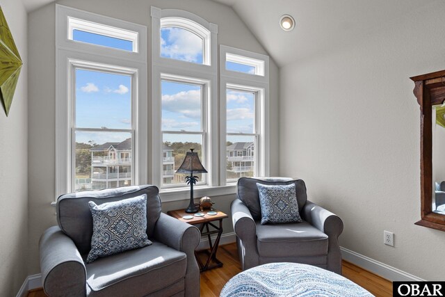 sitting room with wood finished floors, baseboards, lofted ceiling, and a healthy amount of sunlight
