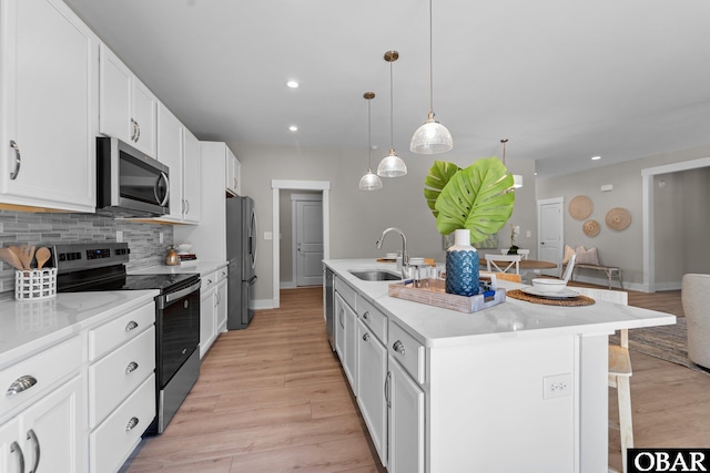 kitchen featuring a breakfast bar, a sink, light wood-style floors, appliances with stainless steel finishes, and tasteful backsplash