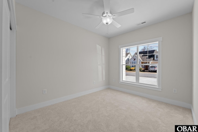 carpeted spare room featuring visible vents, ceiling fan, and baseboards