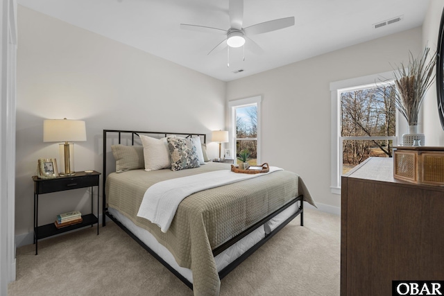 bedroom featuring light carpet, visible vents, baseboards, and ceiling fan