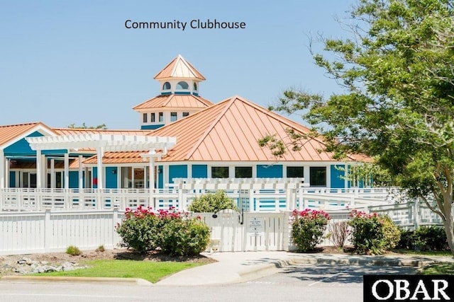 view of front of property with a standing seam roof, fence, a pergola, and metal roof